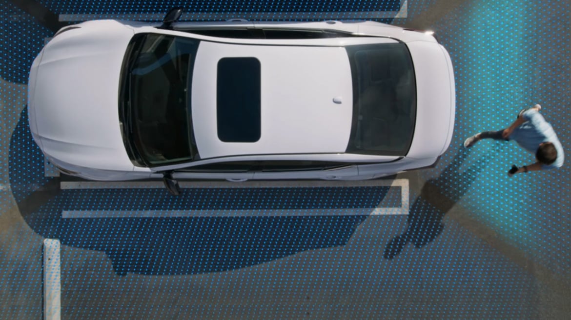 Une personne se promène dans une Nissan Altima 2024 blanche. Le sol est éclairé en bleu, montrant les caractéristiques du bouclier de sécurité 360.