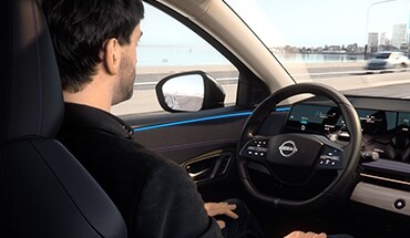 Nissan Ariya 2023, une personne utilisant la conduite mains libres pour illustrer les fonctions d’aide à la conduite et les technologies de sécurité.