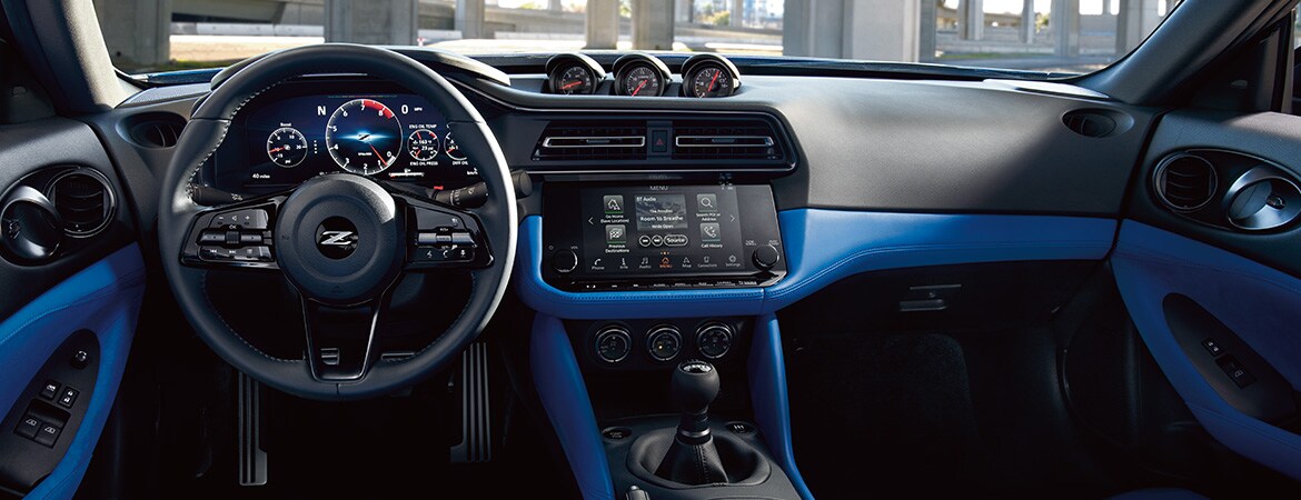 Poste de pilotage intérieur bleu de la Nissan Z 2023 montrant le tableau de bord numérique de performance et le groupe d’instruments à trois indicateurs emblématique.