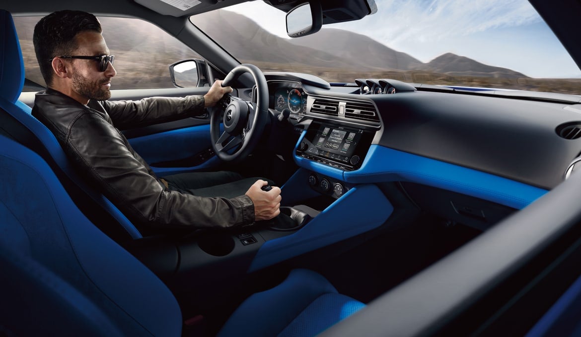 Une personne conduisant une Nissan Z 2024 avec intérieur bleu.