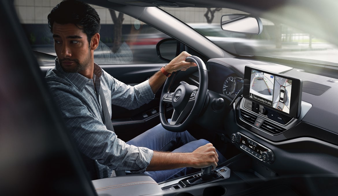 Personne faisant marche arrière dans une Nissan Altima 2024. L’écran tactile affiche l’écran de visualisation du périmètre intelligent. 
