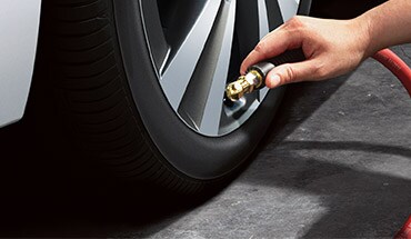 Personne gonflant les pneus du Nissan Armada 2023 pour illustrer le moniteur de pression des pneus.