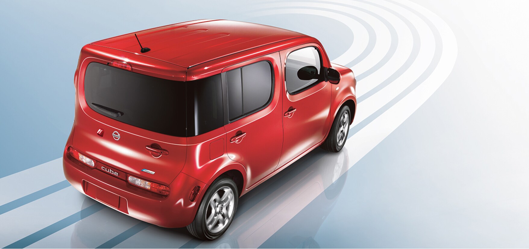 Nissan Cube rouge roulant sur fond bleu pour démontrer la consommation de carburant