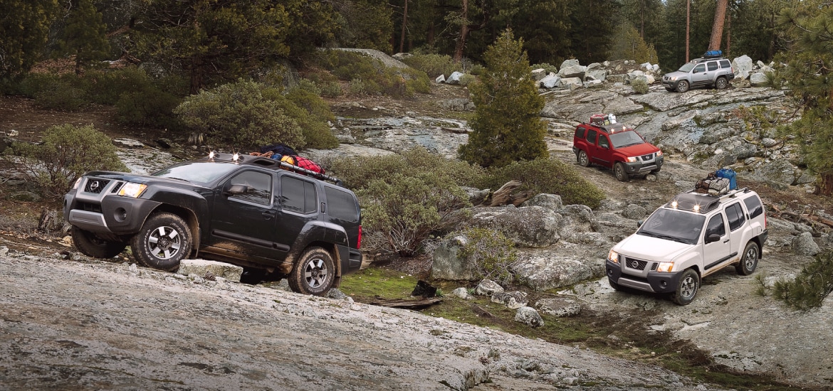 Quatre véhicules Nissan Xterra stationnés sur un terrain rocheux alors qu’ils transportent de l’équipement de camping