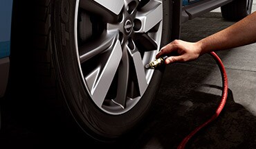 Personne gonflant un pneu de la Nissan Maxima 2023 illustrant le moniteur de pression des pneus.
