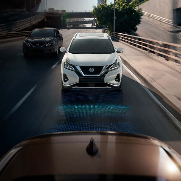 Vue depuis un véhicule devant un Nissan Murano 2024 blanc qui roule. Une illustration bleue se trouve sur la route entre les véhicules pour démontrer le régulateur de vitesse intelligent. 