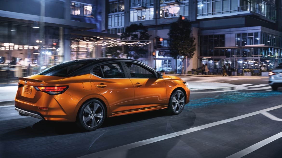 Nissan Sentra 2024 orange roulant en ville la nuit