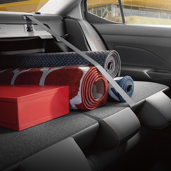 Illustration de la Nissan Versa 2022 montrant les sièges arrière rabattus pour transporter des tapis dans l’aire de chargement.