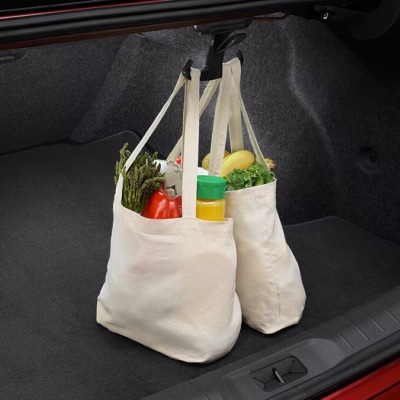 Gros plan de l’espace du coffre de la Nissan Versa 2024 avec crochets pour sacs à provisions