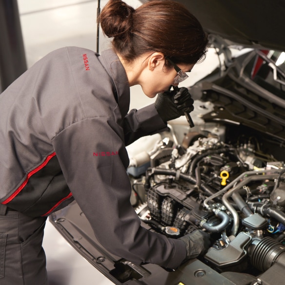 Une technicienne du service technique examine le moteur d’un véhicule Nissan
