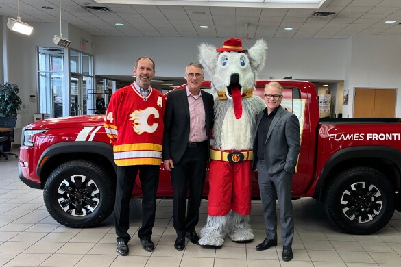 Les représentants du partenariat entre Nissan et les Flames de Calgary avec Harvey le chien devant un Nissan Frontier rouge