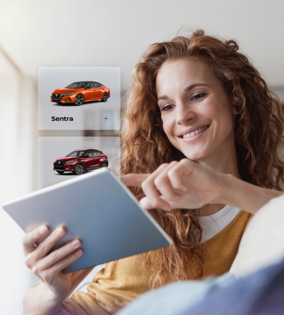 Une personne faisant une recherche dans les stocks de véhicules d’occasion certifiés Nissan sur une tablette à la maison.