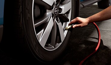 Gros plan sur une personne gonflant un pneu pour montrer le moniteur de pression des pneus du Nissan Murano 2023.